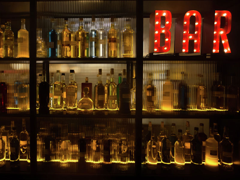 Glass bottles in bar with neon sign