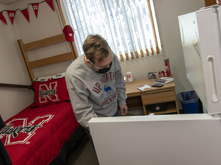 Student looks for snack in refrigerator in residence hall room