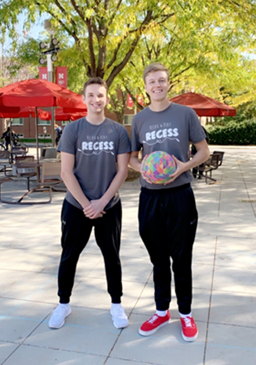 Men posing with a ball at recess
