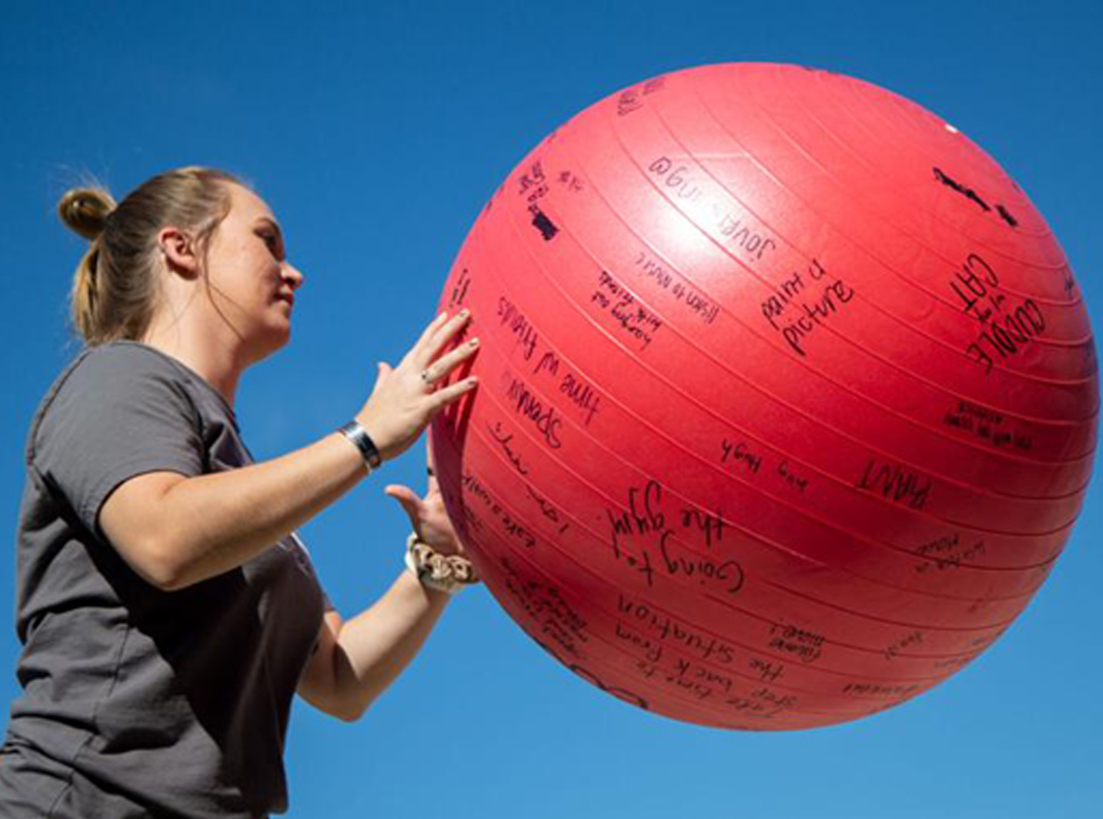 Woman catching a ball covered with written phrases at recess